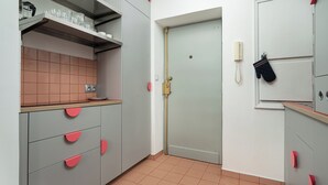 A kitchen with grey cabinets, a tiled backsplash, and a door with a red handle. - RentPlanet - przy Placu Zbawiciela (Warsaw)
