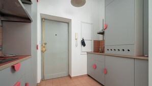 A kitchen with grey cabinets, a white door, and a red oven knob. - RentPlanet - przy Placu Zbawiciela (Warsaw)