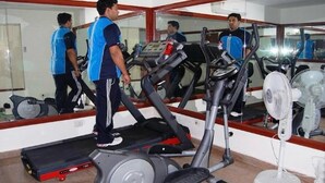 Une salle de sport équipée de tapis de course, d’un ventilateur et d’un miroir.