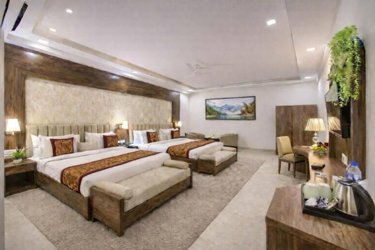 Een hotelkamer met twee bedden, een bureau, een stoel, een televisie en een schilderij aan de muur.