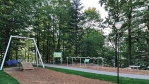 A playground with a swing set, a slide, and a bench. - Studio Rainer mit Pool und Sauna (Freyung)