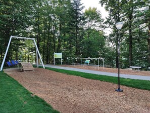 Ein Spielplatz mit Schaukel, Rutsche und einer Bank.
