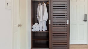 Un dressing avec une porte en bois, une tringle à vêtements et des vêtements soigneusement pliés.