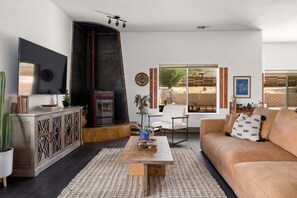 Een woonkamer met een open haard, een bank, een salontafel en een televisie.