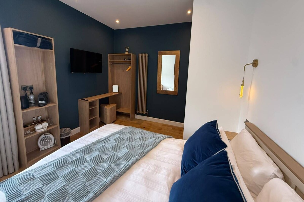 A modern bedroom with a bed, bedside tables, a wardrobe, a mirror, a radiator, and a TV.