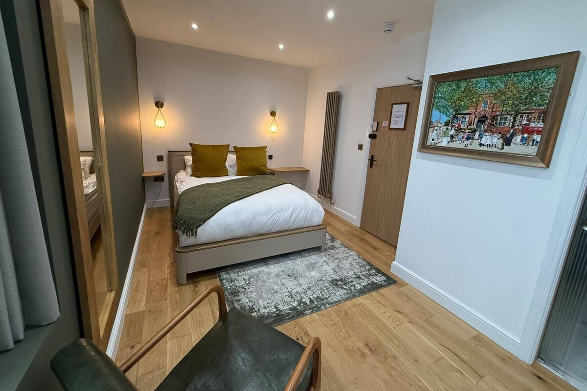 A bedroom with a bed, bedside tables, a painting, and a door.