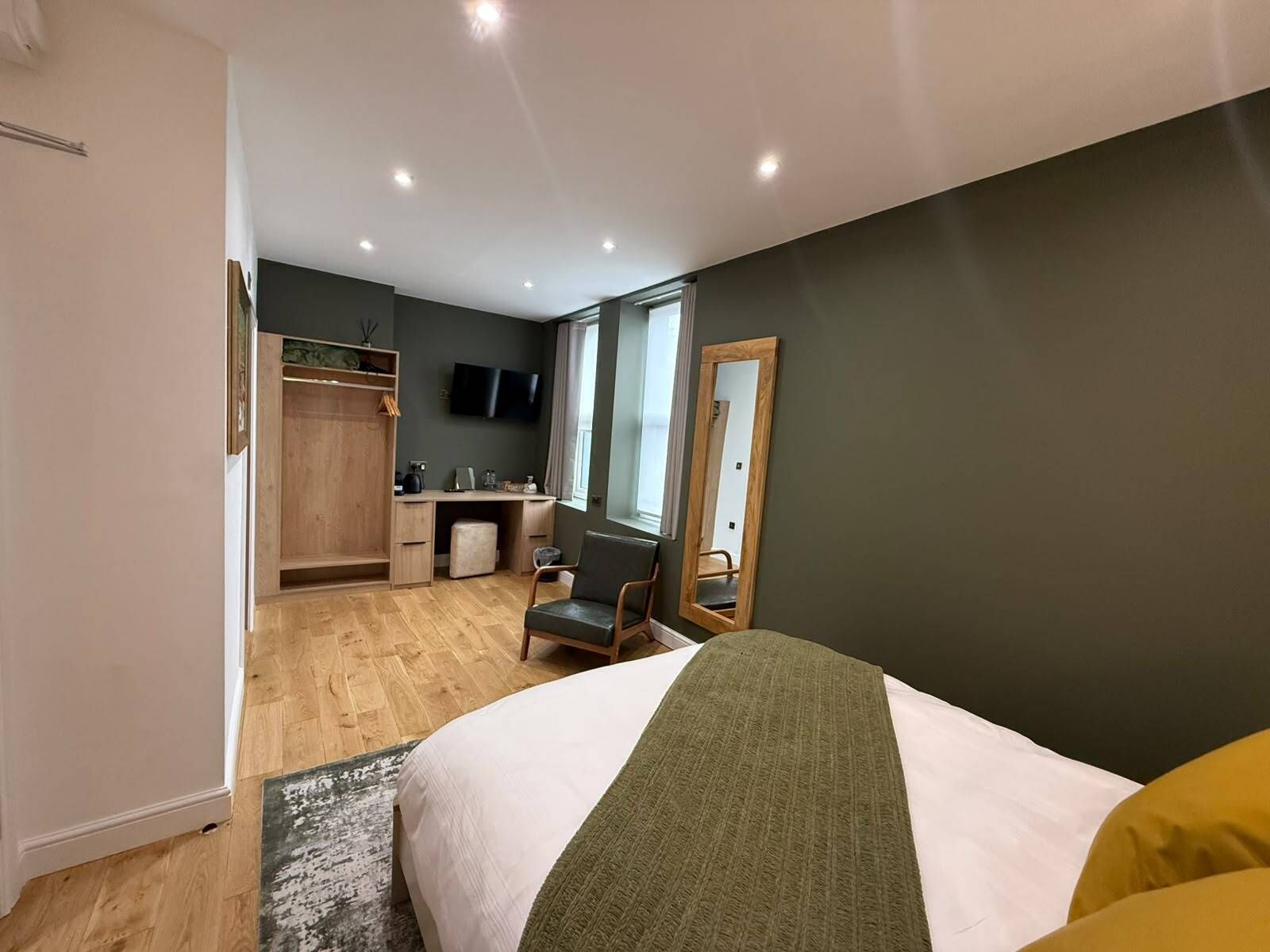A bedroom with a bed, a desk, a chair, a wardrobe, and a television.