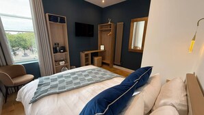 A modern hotel room with a bed, a seating area, a wardrobe, a television, and a window with a view. - Auberge (Lytham St. Anne's)