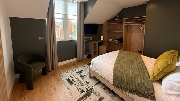 A bedroom with a bed, a desk, a chair, a wardrobe, and a window with curtains. - Auberge (Lytham St. Anne's)