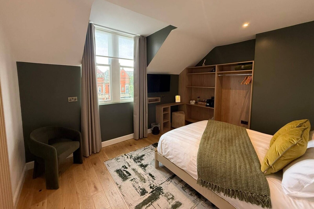 A bedroom with a bed, a desk, a chair, a wardrobe, and a window with curtains.