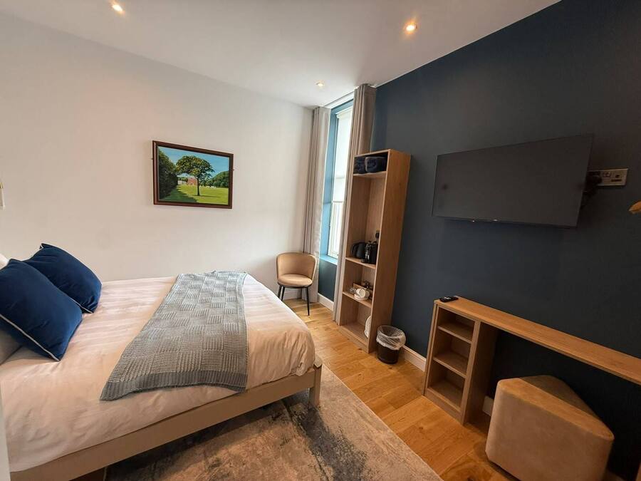 A bedroom with a bed, a chair, a TV, and a wardrobe.