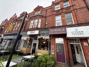 A row of buildings with storefronts, including a hotel, a luxury accommodation, and a tutoring service. - Auberge (Lytham St. Anne's)