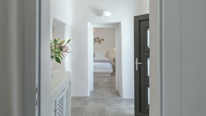 Un pasillo que conduce a un dormitorio con una cama, una lámpara de pared y un adorno en la pared.
