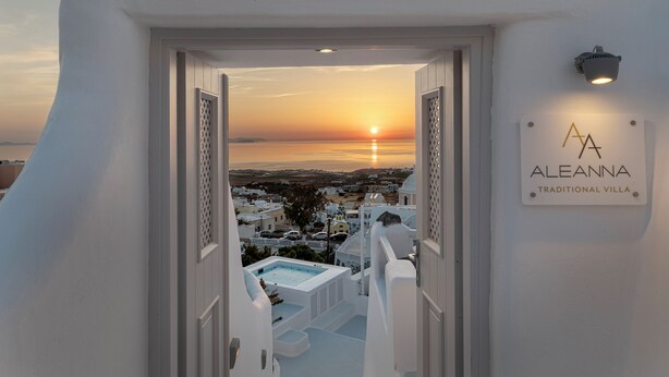 Vista desde una villa tradicional con un letrero que dice "ALEANNA TRADITIONAL VILLA" y un atardecer de fondo.