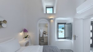 Una habitación de hotel moderna con una cama grande, un baño pequeño y vistas al mar.
