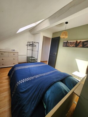 Une chambre à coucher comprenant un lit, une commode, une armoire et un portant à vêtements.