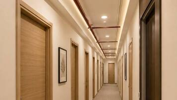 A hotel corridor with doors on both sides, carpeted flooring, and recessed lighting.