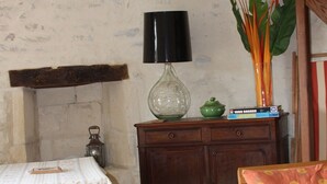 Une pièce comprenant une table en bois, une chaise, un meuble, une lampe et une plante.