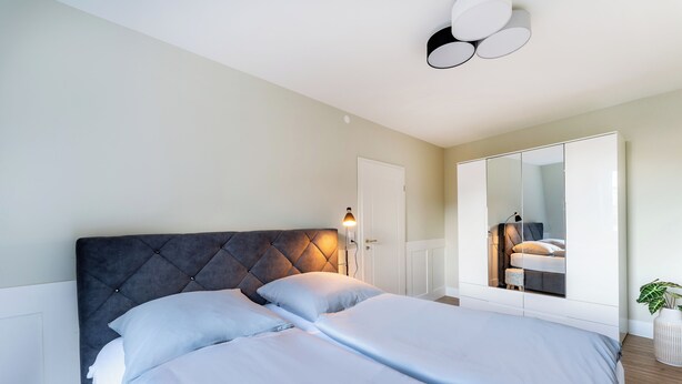 Un dormitorio con una cama grande, un armario y un espejo.