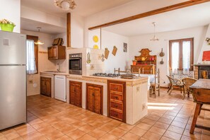 A kitchen with a refrigerator, oven, sink, and wooden cabinets. - Alloggio turistico Isola dei Cavalli (Manziana)