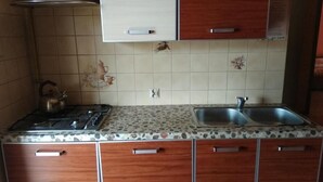 Una cucina con piano cottura a gas, due lavelli, mobili in legno e piastrelle decorative.