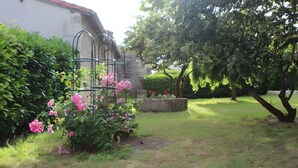 A garden with a metal trellis, flowering plants, and a stone wall.