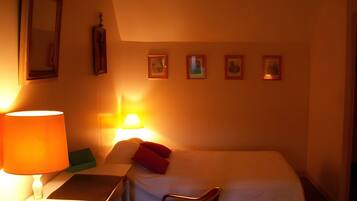 Ein Hotelzimmer mit einem Bett, einem Nachttisch, einer Lampe und vier gerahmten Bildern an der Wand.