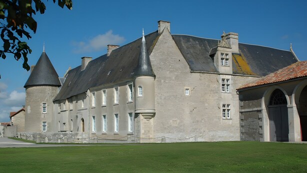 A historic building with multiple towers, a courtyard, and a large arched entrance.