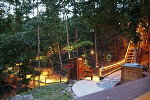 A forested area with a wooden structure, a ladder, and a pathway. - Bear Claw Tepee | Near Dollywood | Resort Access (Sevierville)