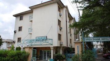 Un edificio de varios pisos con un letrero que dice 'ABUJA DANNIC HOTELS' y una escalera metálica que lleva a la entrada.