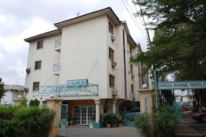 Un edifici de diversos pisos amb un cartell que diu 'ABUJA DANNIC HOTELS' i una escala metàl·lica que condueix a l'entrada.