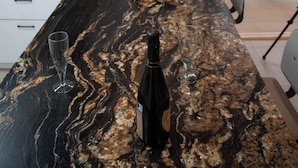 A kitchen with a marble countertop, a wine bottle, and glasses. - Villa Petra Arenal dén Castell Menorca (Es Mercadal)