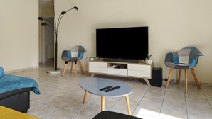 Un salon équipé d’un téléviseur à écran plat, de deux fauteuils, d’une table basse et d’un lampadaire.