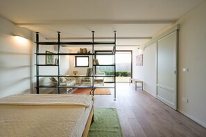 Una camera da letto con un letto, un divano, una sedia, una libreria e vista sull'esterno.