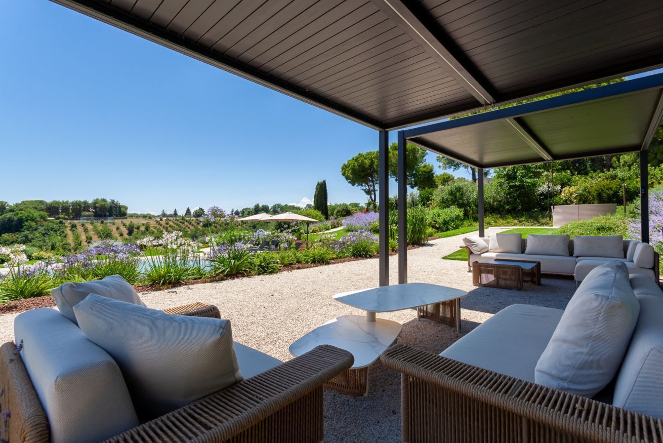 An outdoor seating area with wicker furniture and a view of a landscaped garden.