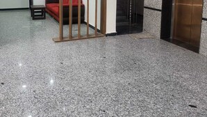 Un vestíbul ampli amb un sofà vermell, una separació de fusta, un ascensor i una escala.