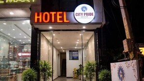 Entrada d'un hotel amb un cartell que indica 'HOTEL CITY PRIDE' i una botiga de 'L M ART' visible al fons.