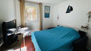 Ein Hotelzimmer mit Bett, Schreibtisch mit Stuhl, Fernseher und einem Fenster mit Vorhängen.