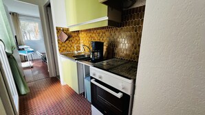 Eine kleine Küche mit Herd, Spüle und Kaffeemaschine.