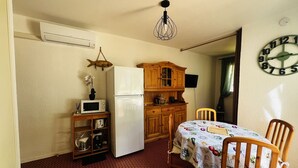 Eine kompakte Küche mit Kühlschrank, Mikrowelle, Holzschränken und einem Esstisch mit Stühlen.