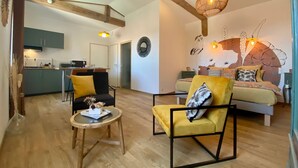 A modern interior with a dining area, kitchen, and a bedroom with a bed and nightstand.