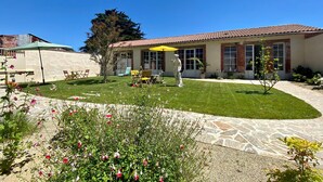 A house with a patio, outdoor furniture, a statue, and a well-maintained garden.