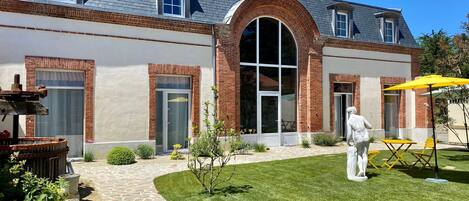 A two-story house with a brick facade, a large arched window, and a stone pathway leading to the entrance.