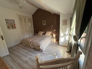 A bedroom with a bed, bedside table, lamp, and a window with curtains.