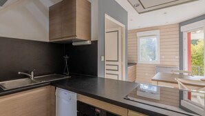 A modern kitchen with a dishwasher, a sink, and a window overlooking greenery. - Cozy riverside gîte - 4 guests (Boismont)