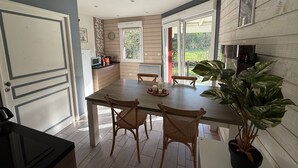 A modern kitchen with a dining area, wooden flooring, and large windows. - Cozy riverside gîte - 4 guests (Boismont)