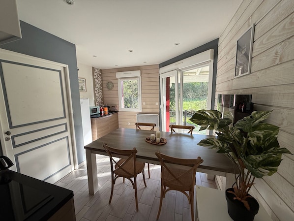 A modern kitchen with a dining area, wooden flooring, and large windows.