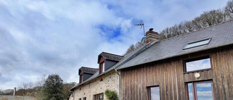 A rustic building with a stone facade, wooden siding, and a sloped roof.
