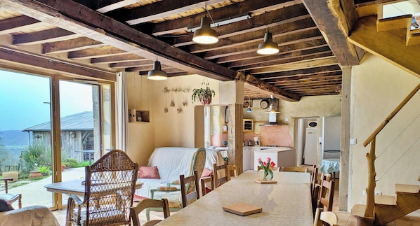 A rustic interior with a dining area, kitchen, and large windows.