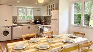 A kitchen with a dining area, including a table set for four with glasses and plates, a washing machine, and a refrigerator. - House with parking - 6 guests (La Palmyre)